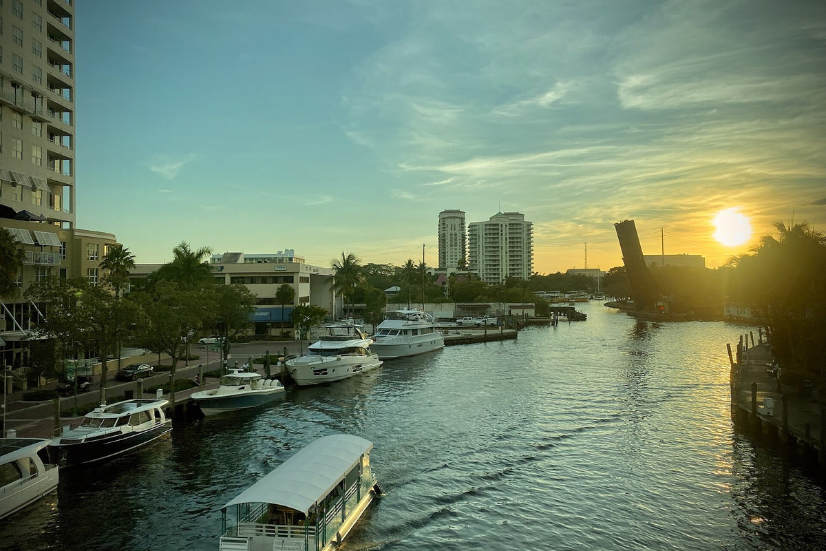 Boats and waterfront buildings along a Fort Lauderdale waterway in warm sunset light