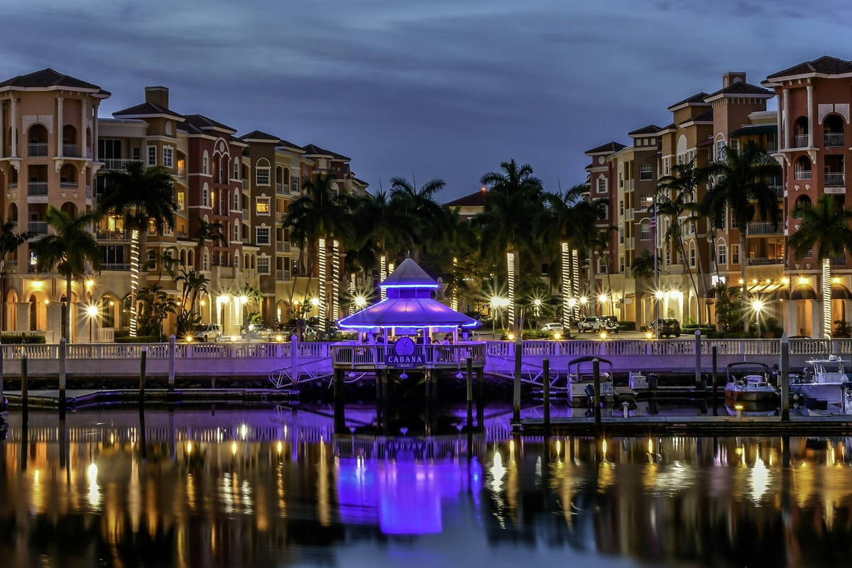 Lit waterfront buildings and purple pavilion reflected in Naples Bay at night in 2017